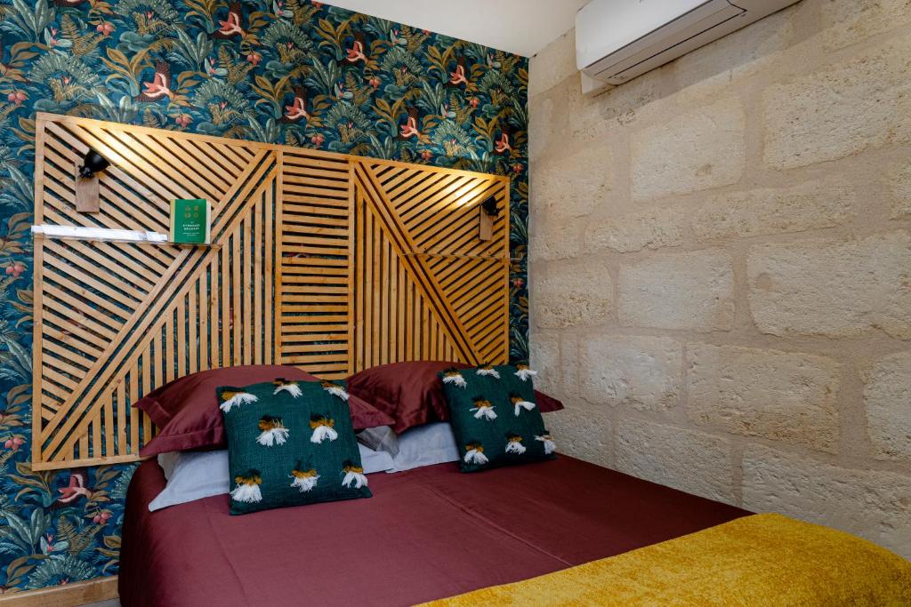 a room with a bed with pillows and a wall at Hôtel Particulier - Bordeaux St Jean in Bordeaux