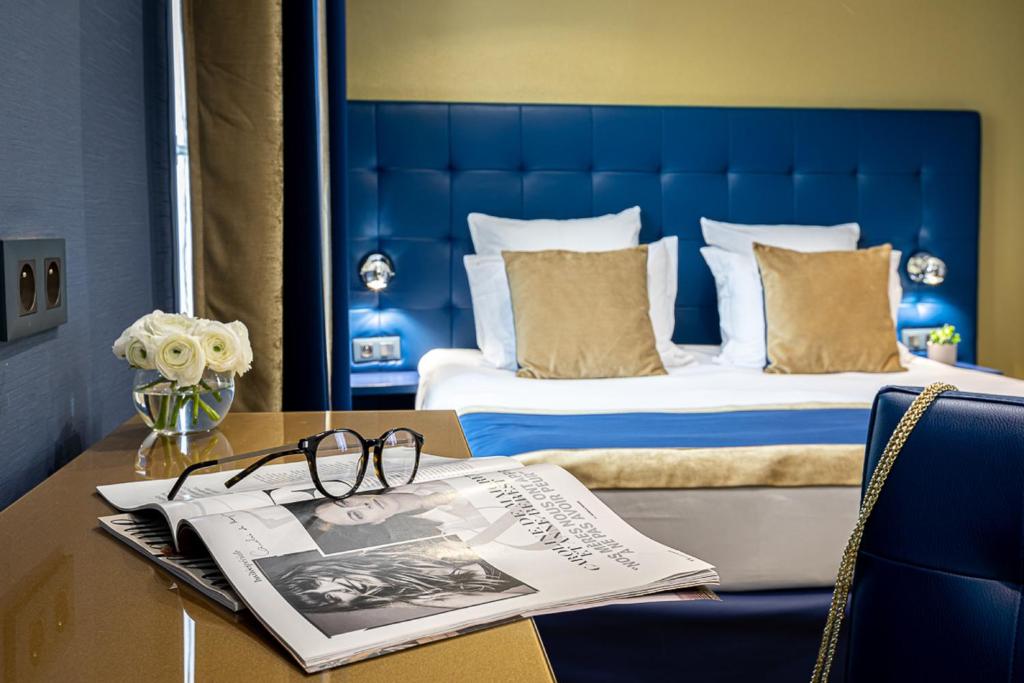 a hotel room with a bed and a table with a newspaper at Trianon Gare de Lyon in Paris