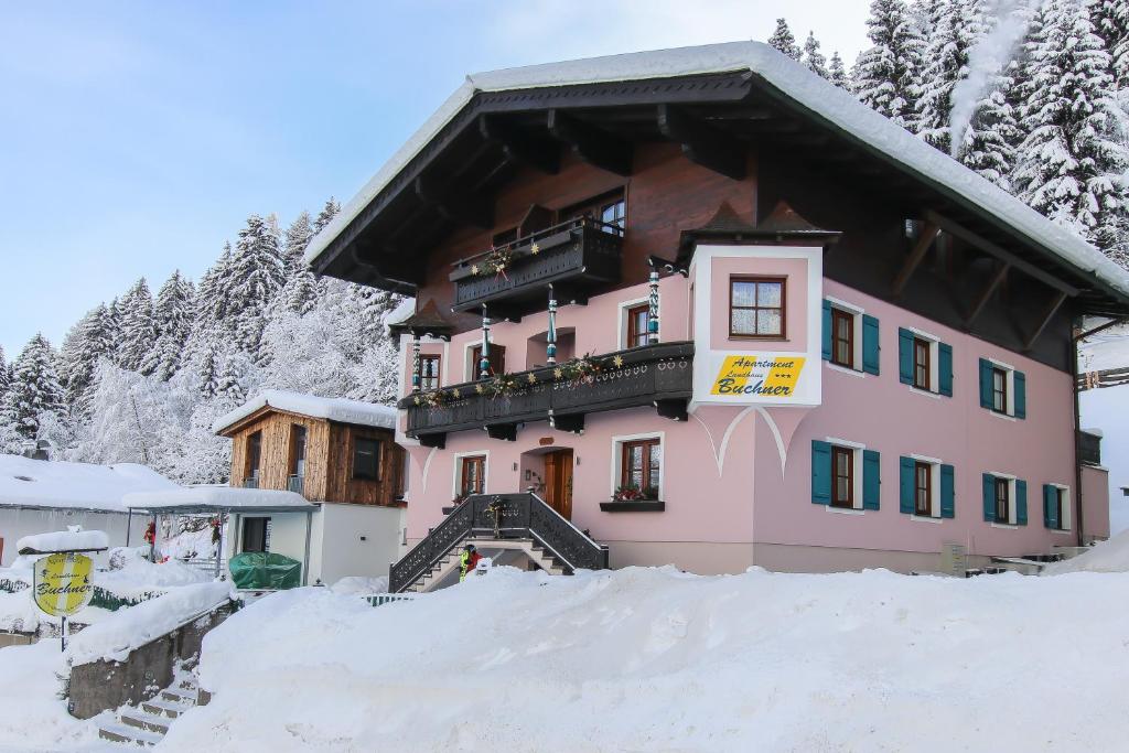 ein rosafarbenes Gebäude mit Schnee davor in der Unterkunft Apartment Landhaus Buchner in Zell am See
