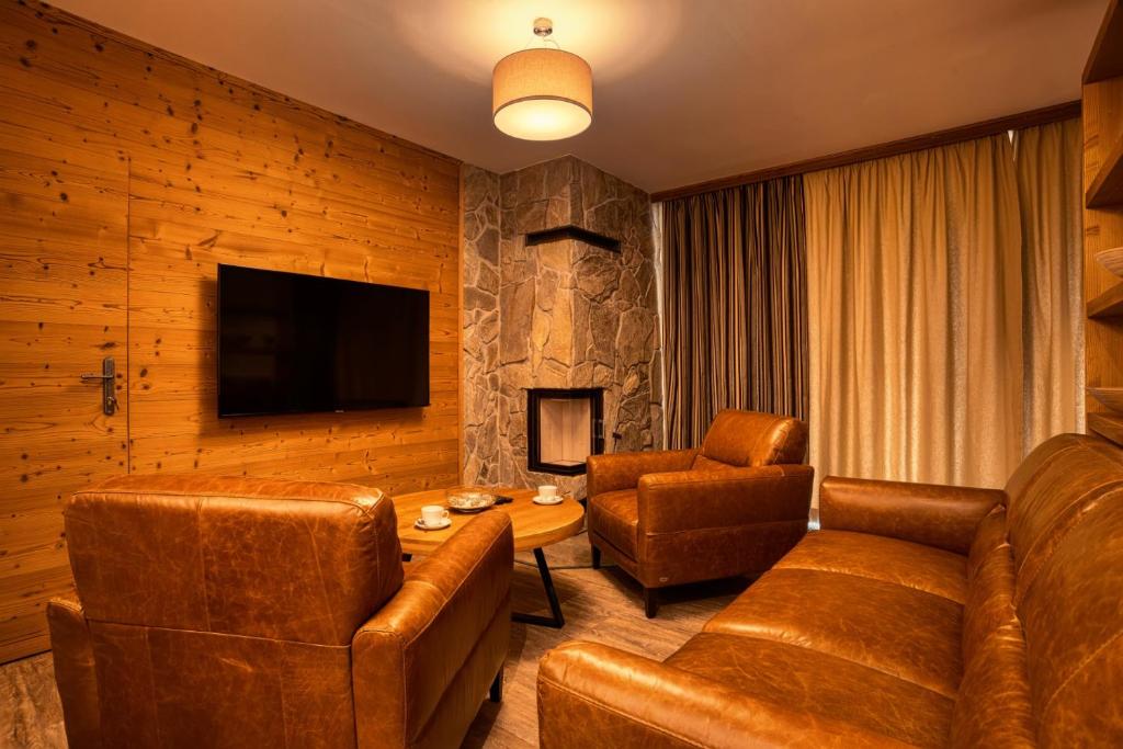 a living room with leather furniture and a television at DaSus Lux&Wellness Apartments Sosana in Demanovska Dolina