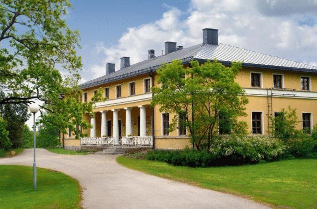 un gran edificio amarillo con un árbol delante de él en Kyyhkylä Hotel and Manor, en Mikkeli