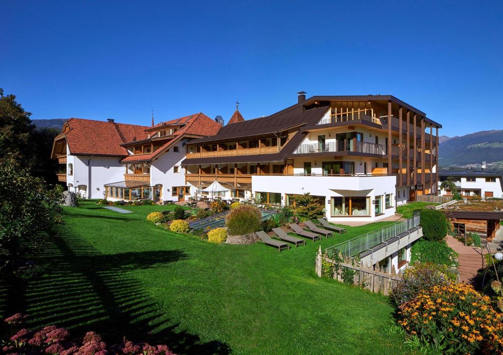 a large building with a lawn in front of it at Hotel Mühlgarten in San Lorenzo di Sebato