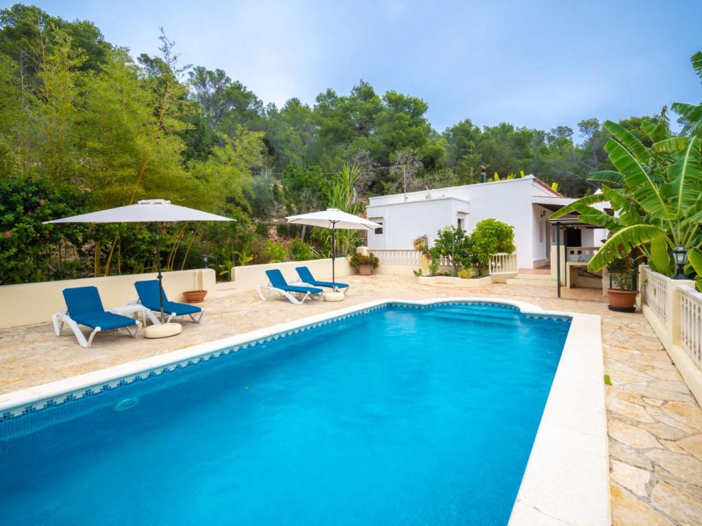 a swimming pool with blue chairs and umbrellas at Holiday Home Can Toni Mari by Interhome in Sant Carles de Peralta