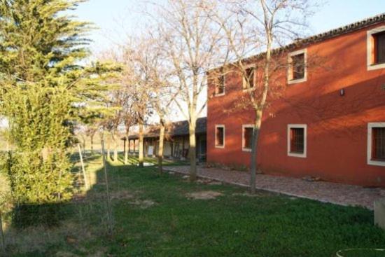 ein rotes Backsteingebäude mit Bäumen davor in der Unterkunft La Dehesa Boyal in Los Yébenes