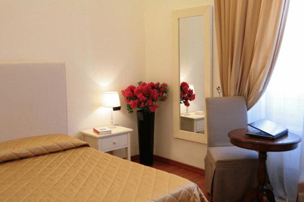 una camera con un letto e un vaso di fiori rossi di B&B Magnifico Messere a Firenze