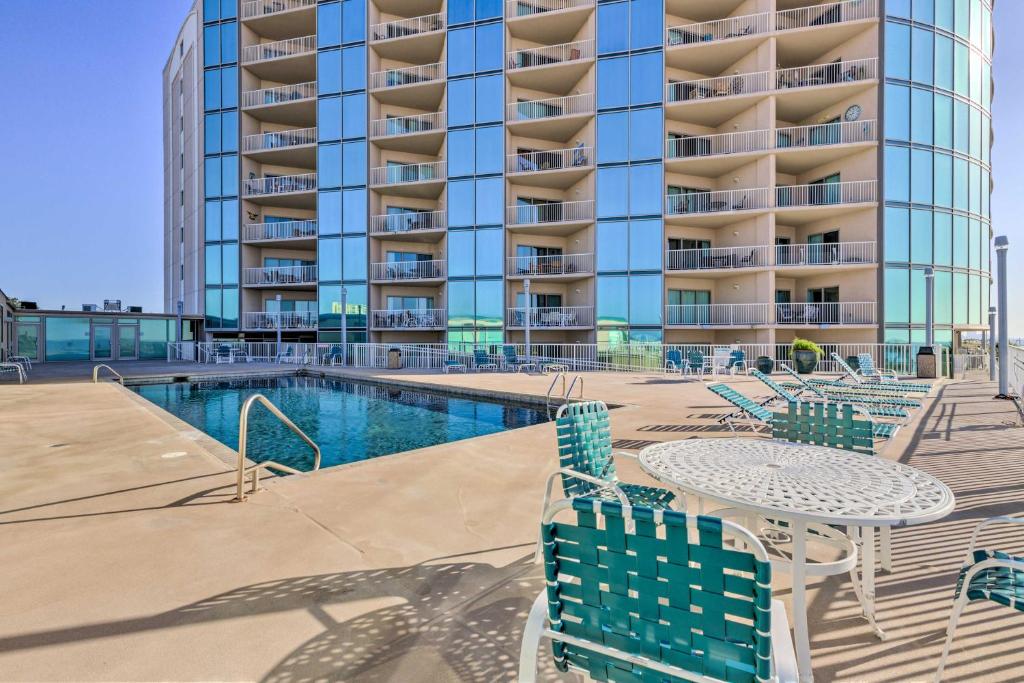a pool with chairs and a table in front of a building at Sunny Beachfront Biloxi Condo with Resort Amenities! in Biloxi