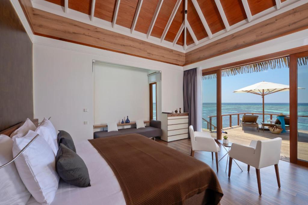 a bedroom with a bed and a view of the ocean at Kandolhu Maldives in Himandhoo 