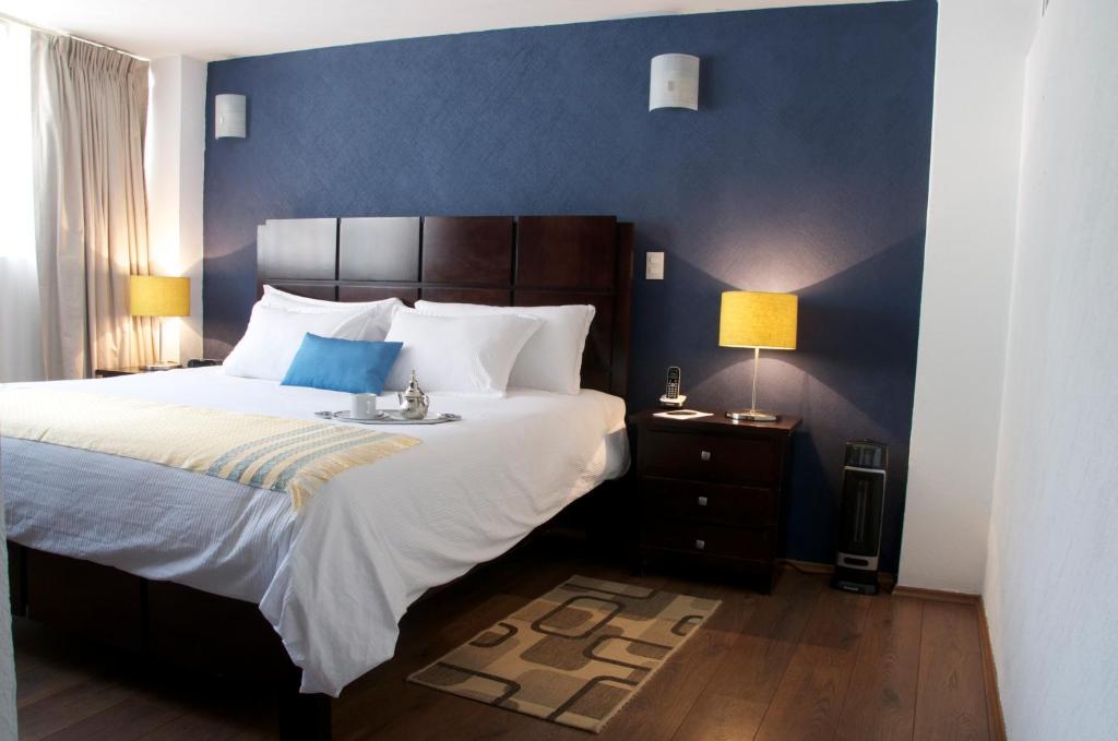 a bedroom with a large bed with a blue wall at Suites Berna 12 in Mexico City