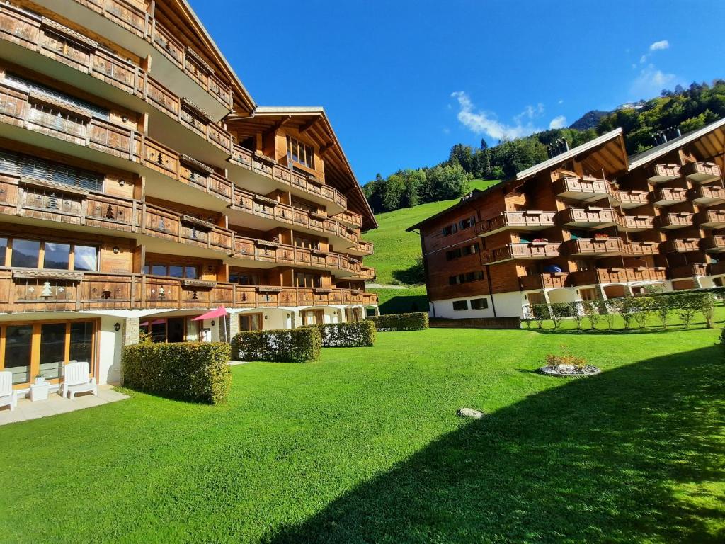 a large apartment building with a lawn in front of it at Appartement et studio, Val d'illiez in Val-d'Illiez