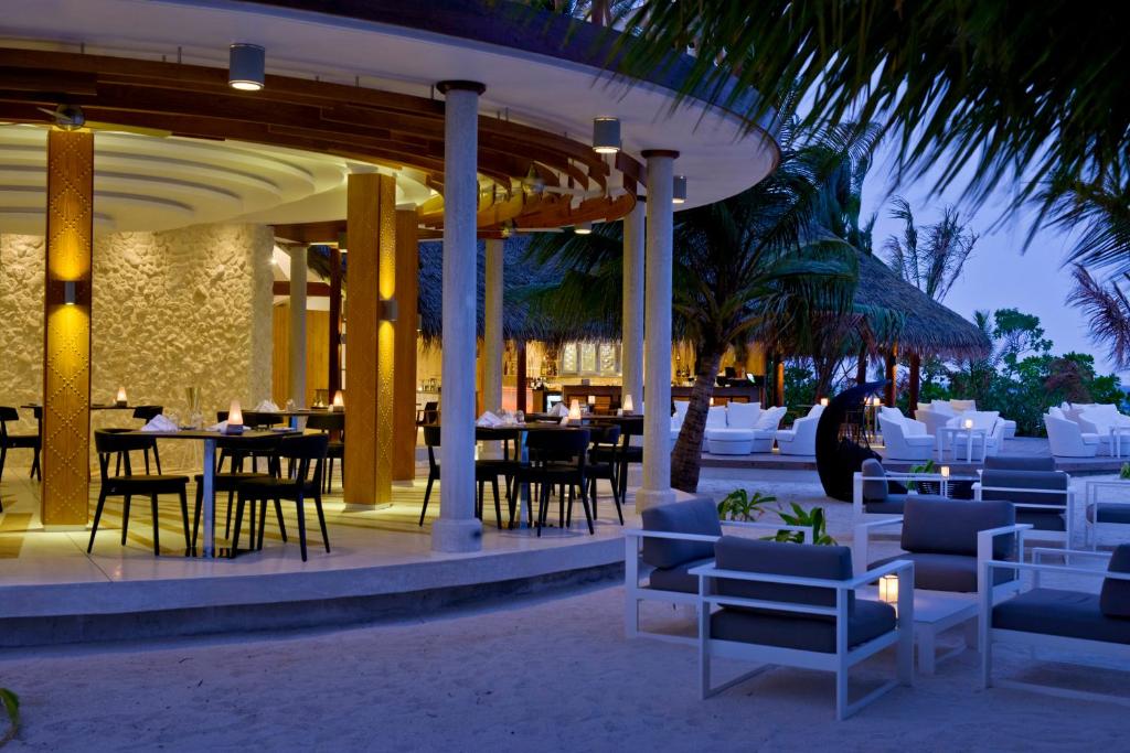 a restaurant on the beach with tables and chairs at Kandolhu Maldives in Himandhoo 