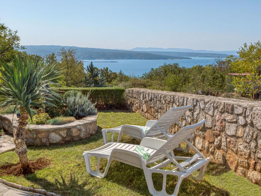 two white chairs sitting on the grass near a stone wall at Holiday Home Lovreno - CKV126 by Interhome in Crikvenica
