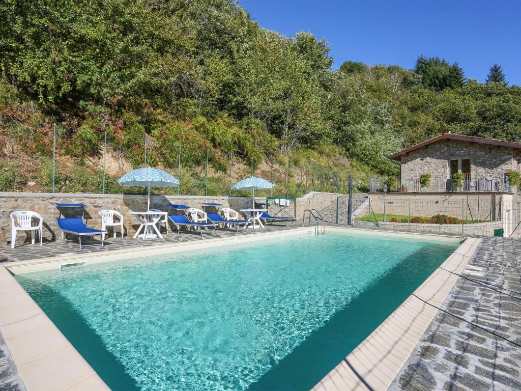 a swimming pool with chairs and umbrellas next to a house at Apartment Caminetto - CNG177 by Interhome in Magnano