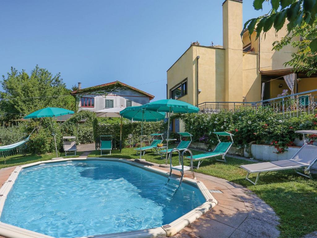 a pool with chairs and umbrellas in a yard at Holiday Home Villetta nel Verde by Interhome in Montaione
