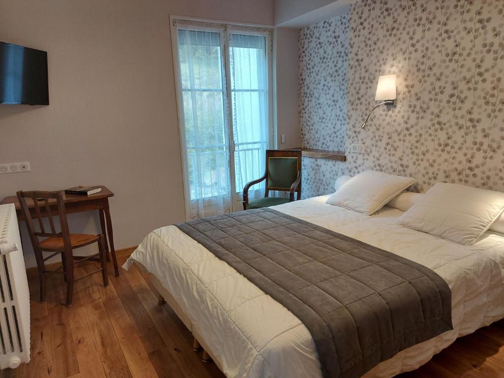 a bedroom with a bed and a desk and a chair at Hôtel La Montagne Fleurie in Barèges