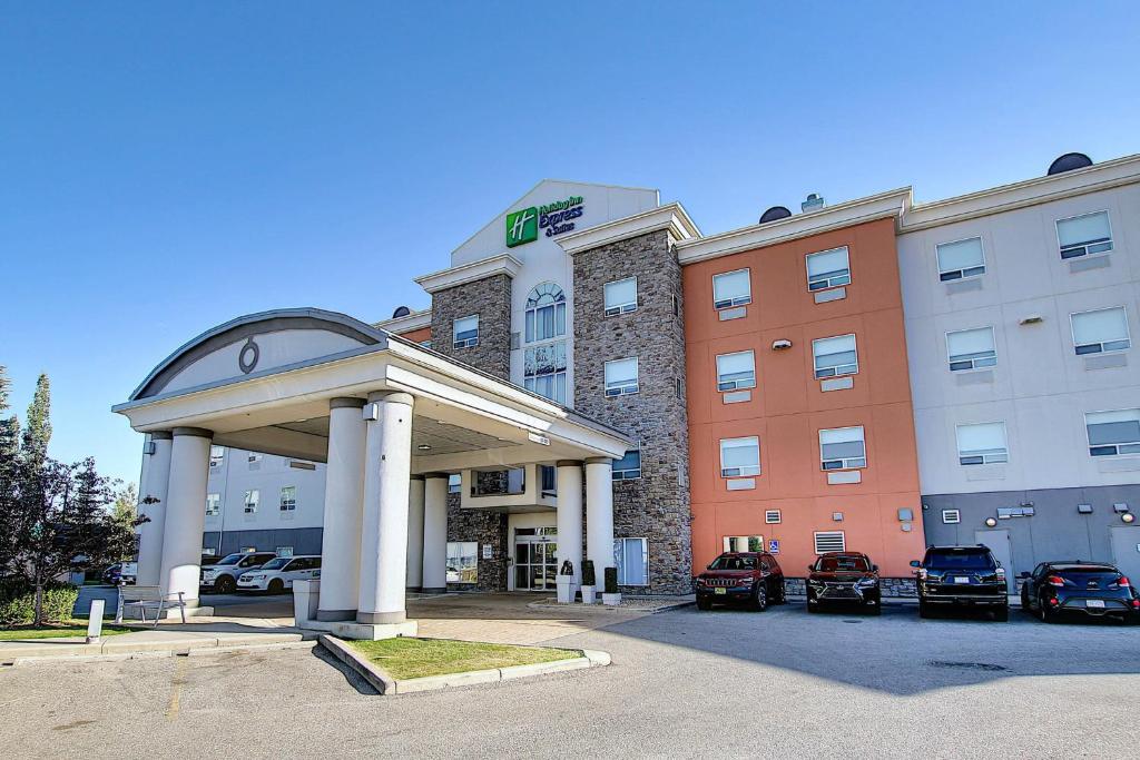 um hotel com carros estacionados num parque de estacionamento em Holiday Inn Express Airport Calgary, an IHG Hotel em Calgary