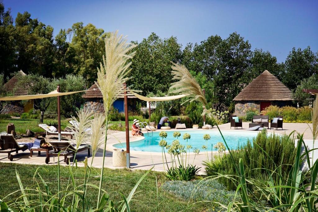 a swimming pool in a garden with chairs and a table at Is Cheas wine farm boutique hotel in San Vero Milis