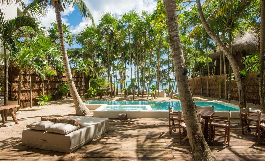 a pool with palm trees and chairs and a couch at Privada Soliman Bay villa pets welcome! in Tulum