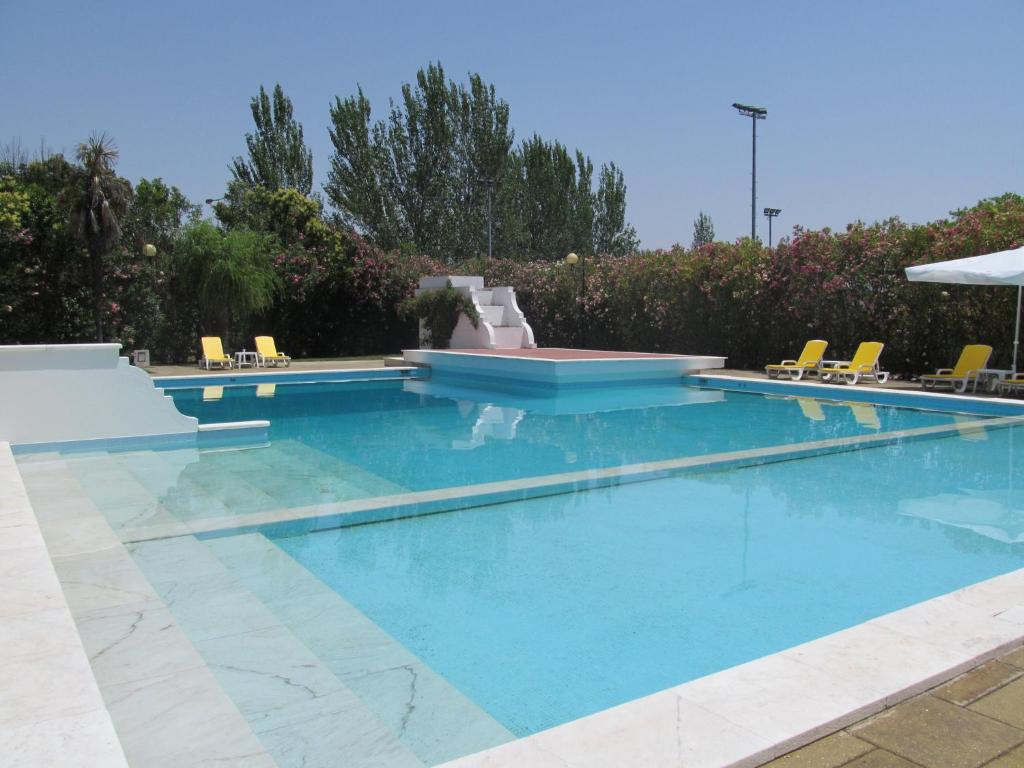a swimming pool with blue water and yellow chairs at SL Hotel Santa Luzia – Elvas in Elvas