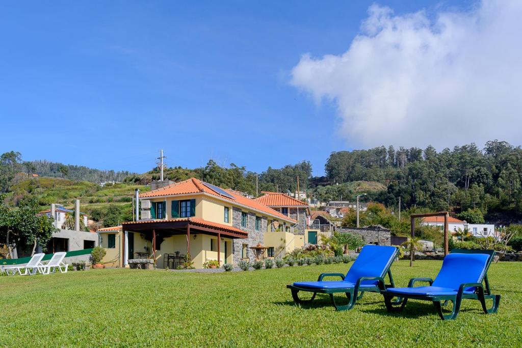 zwei blaue Stühle im Gras vor einem Haus in der Unterkunft Recanto das Florenças (1) in Arco da Calheta