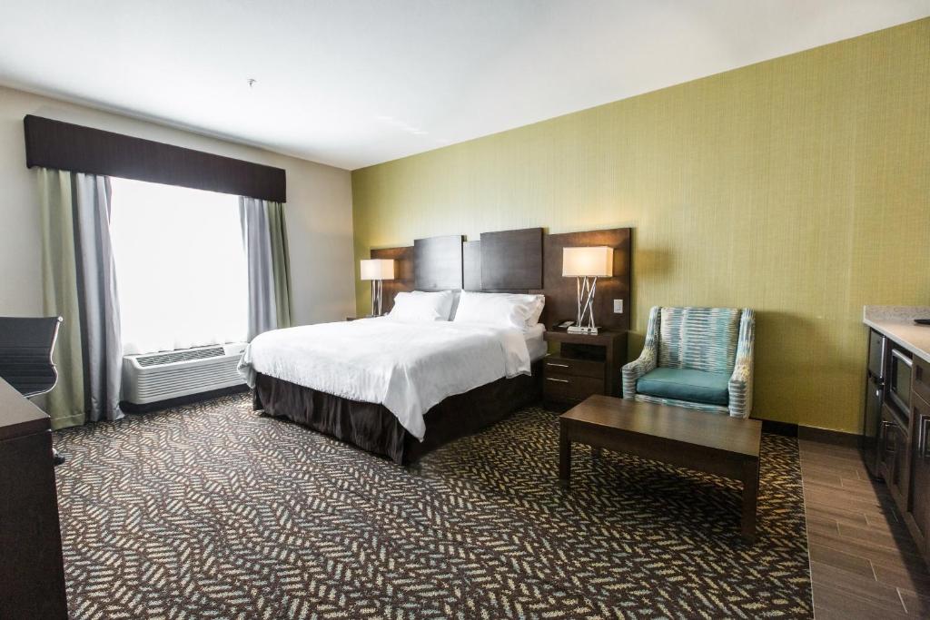 a hotel room with a bed and a chair at Holiday Inn Express & Suites Spruce Grove - Stony Plain by IHG in Spruce Grove