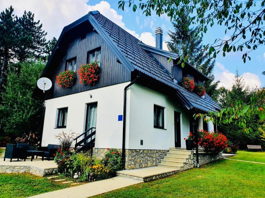 una casa blanca con flores en el techo en Plitvice Retreat Apartments, en Rudanovac