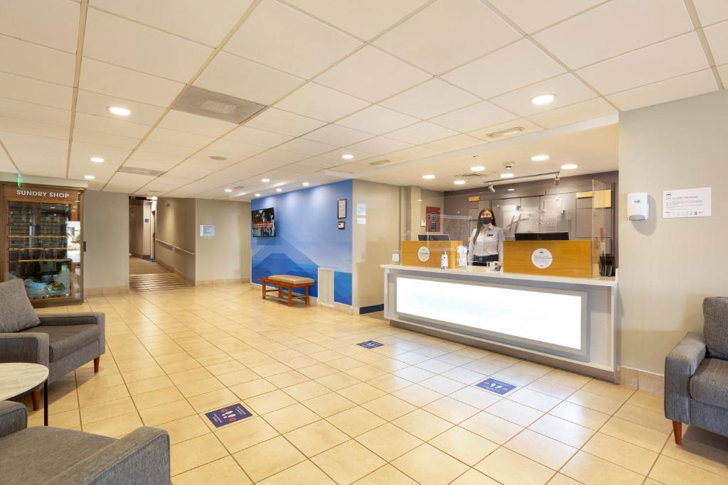 a lobby of a hospital with a counter and a woman at Holiday Inn Express San Jose Costa Rica Airport by IHG in Alajuela City