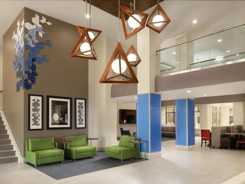 歐文的住宿－歐文達拉斯/沃斯堡機場北智選假日酒店及套房，一个带绿色椅子和灯的办公大厅