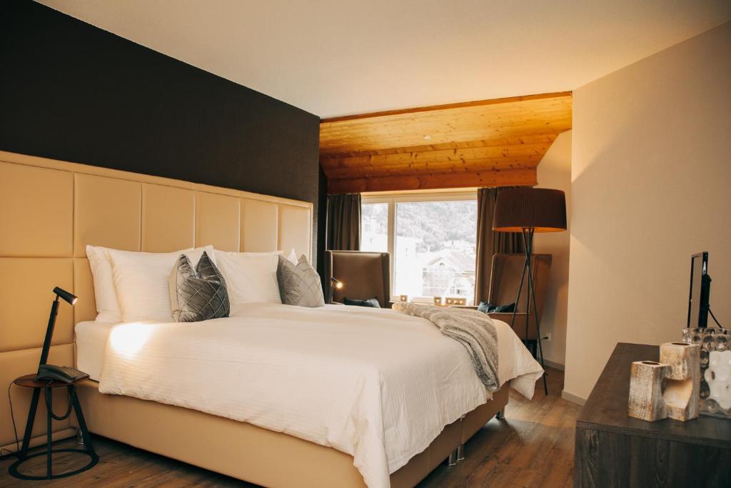 um quarto com uma grande cama branca e uma janela em Hotel Dakota em Meiringen