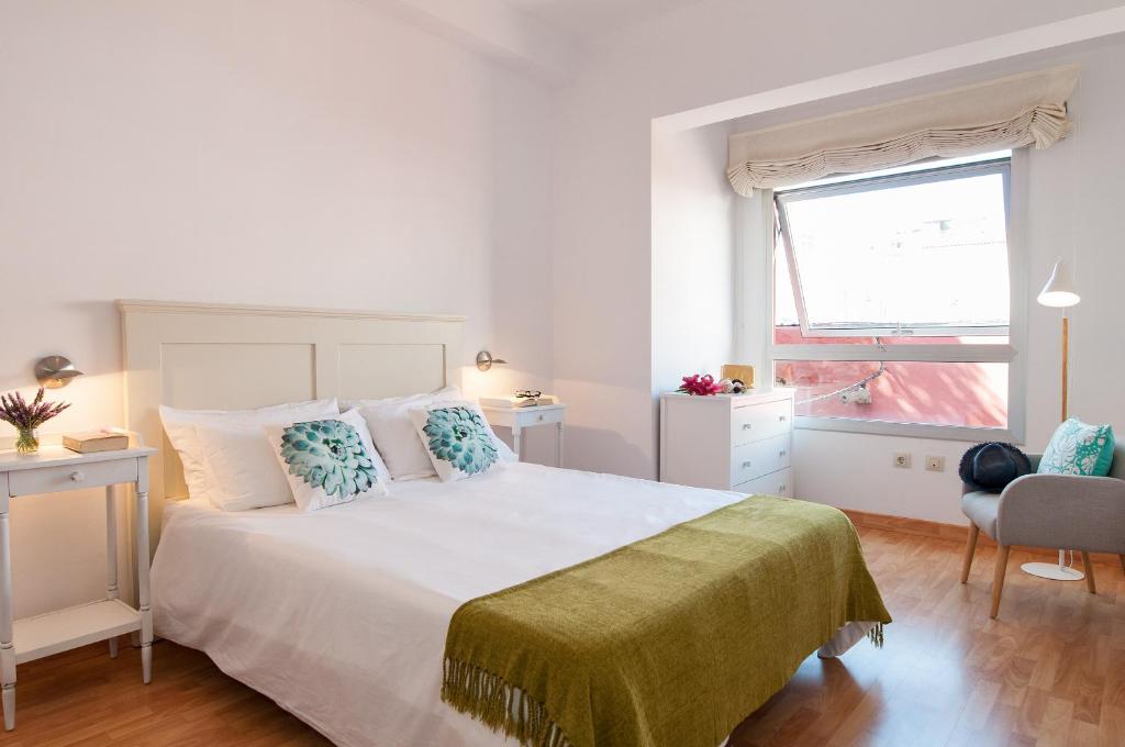 Flatguest Triana في لاس بالماس دي غران كاناريا: غرفة نوم بيضاء مع سرير كبير ونافذة