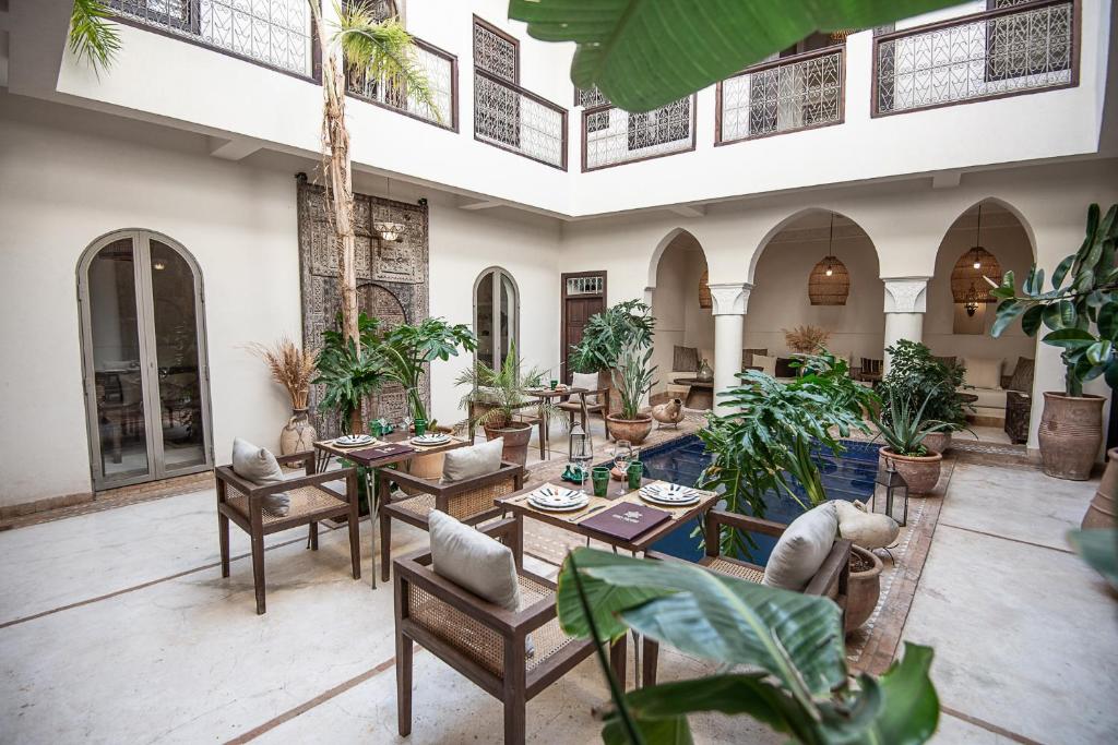 an indoor courtyard with tables and chairs and plants at Riad Farhan in Marrakesh