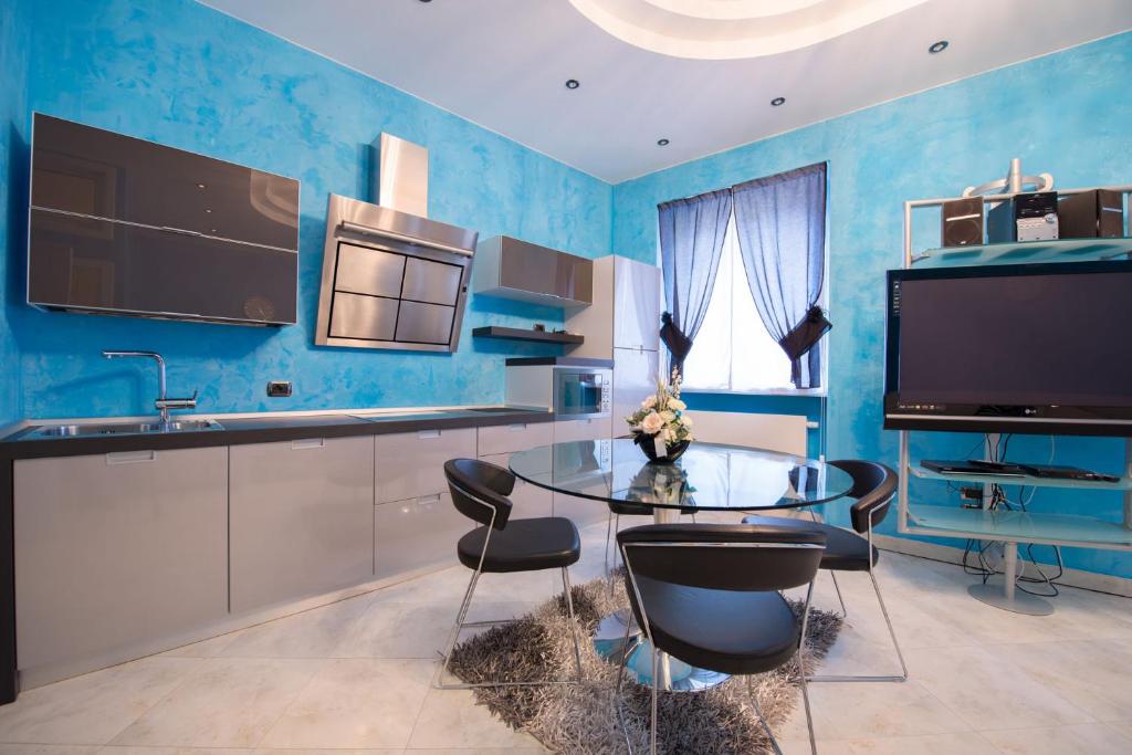 niebieska kuchnia ze szklanym stołem i krzesłami w obiekcie Appartamenti Luxury Arco w Arco