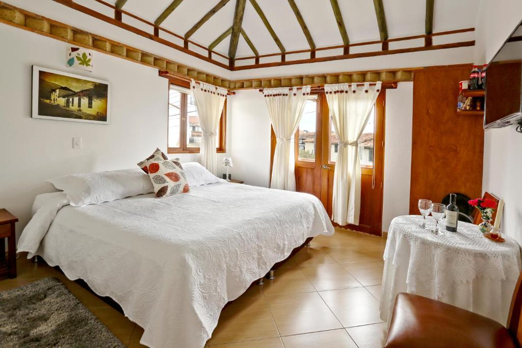 a bedroom with a white bed and two tables at Hotel Villa del Angel in Villa de Leyva