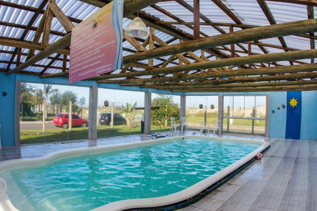 a large swimming pool in a building with a roof at Hotel Mar e Sol - Capão da Canoa in Capão da Canoa