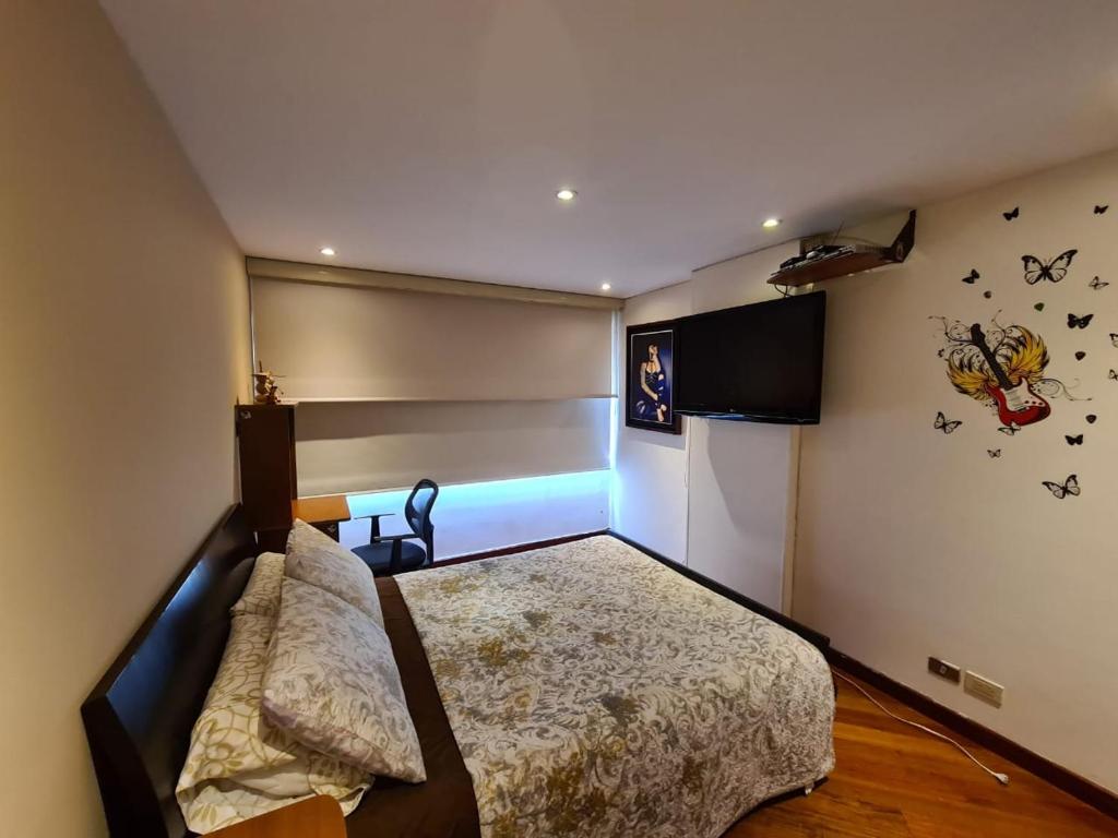 Un dormitorio con una cama y un televisor en la pared. en Tu Hogar cerca a la zona T, en Bogotá