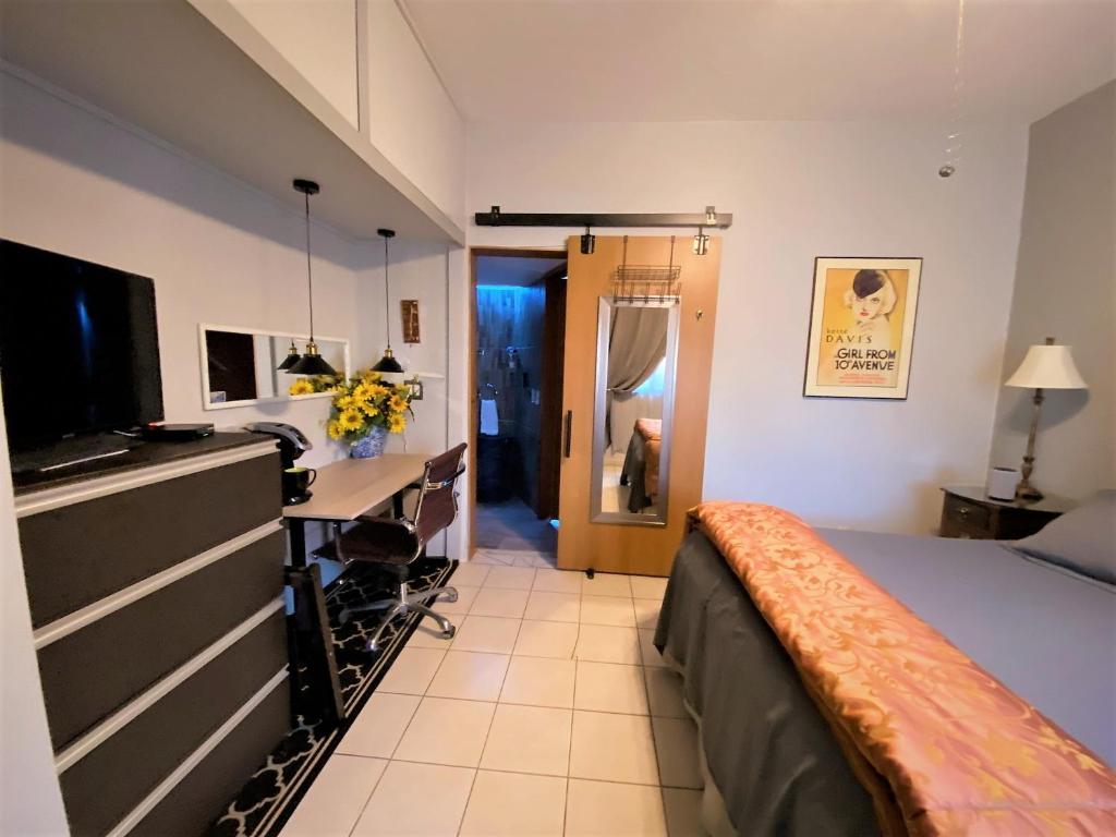 a bedroom with a bed and a desk and a television at Dickinson Guest House, Guadalajara Expo in Guadalajara