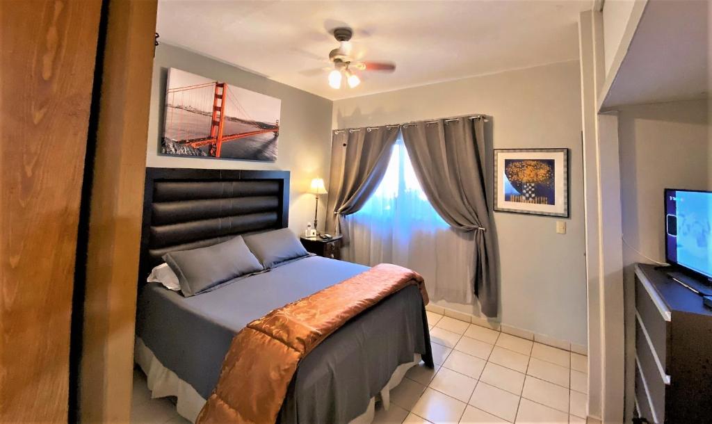 a bedroom with a bed and a tv and a window at Dickinson Guest House, Guadalajara Expo in Guadalajara