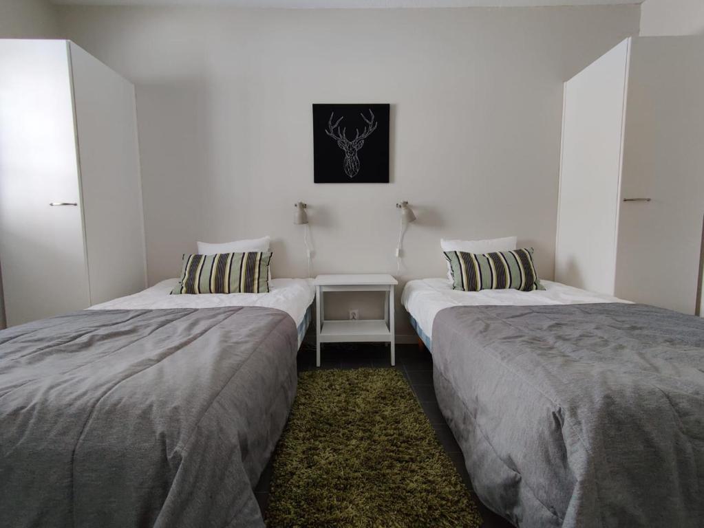 two beds in a white room with a table at Rauhalahti Holiday Homes in Kuopio