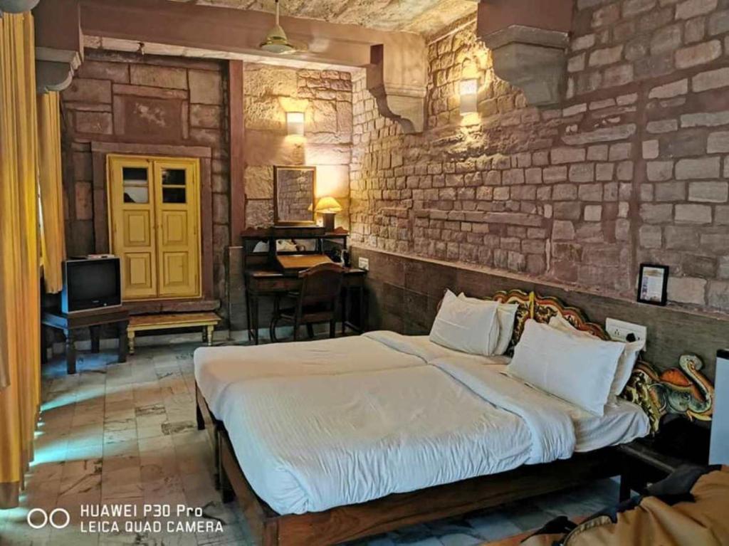 een slaapkamer met een bed en een bakstenen muur bij Krishna Prakash Heritage Haveli in Jodhpur