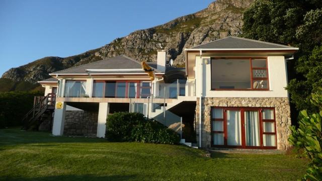 a large house with a mountain in the background at Jocks Place (on the sea) in Bettyʼs Bay