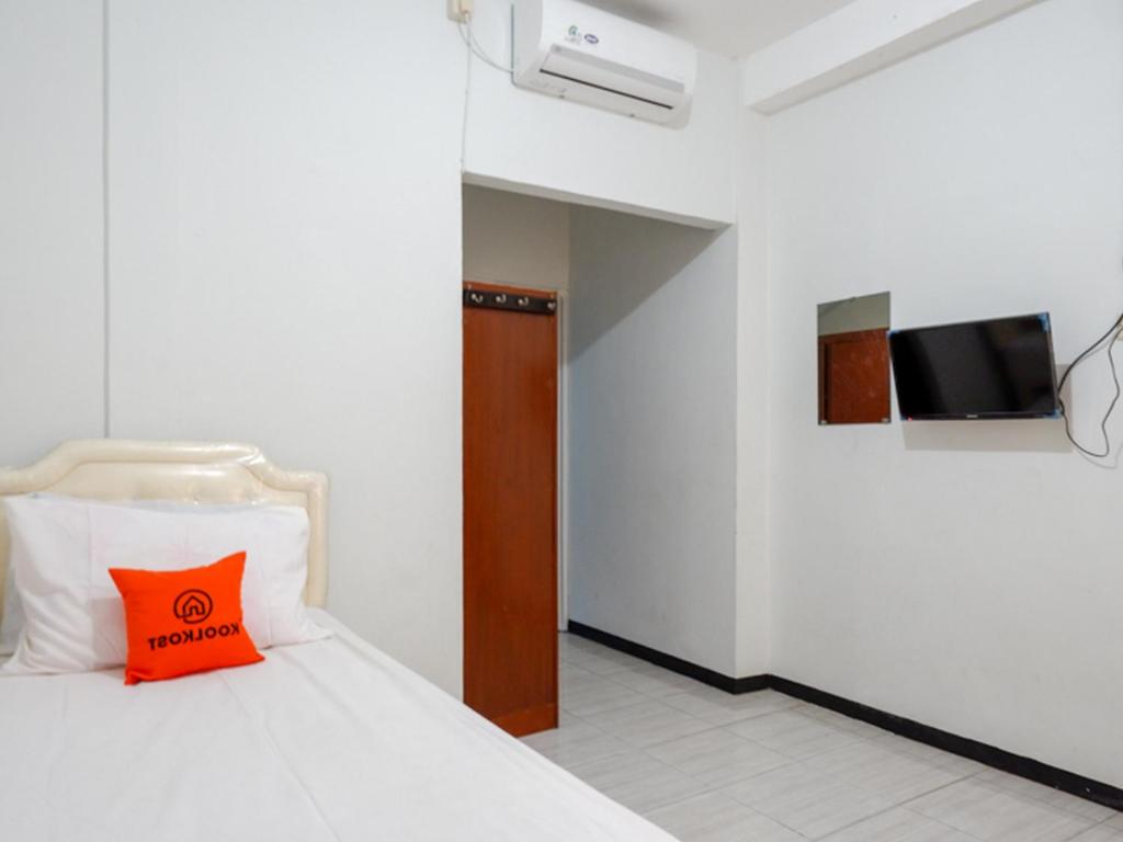 a bedroom with a bed with a orange pillow on it at KoolKost Syariah near RSUP Dr Kariadi Semarang Minimum Stay 6 nights in Jomblang