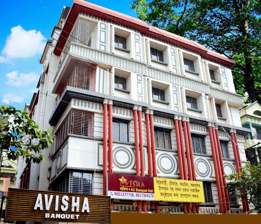 duży biały budynek z czerwonymi kolumnami w obiekcie Hotel Avisha w mieście Kolkata