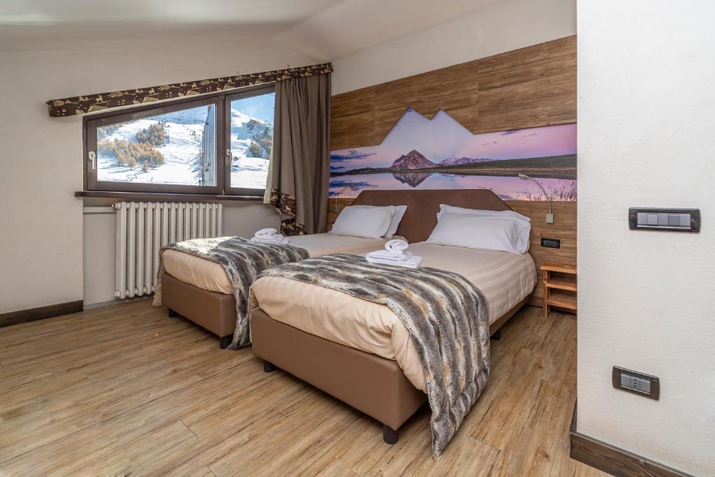 1 dormitorio con 2 camas y un cuadro en la pared en Hotel Du Col en Sestriere
