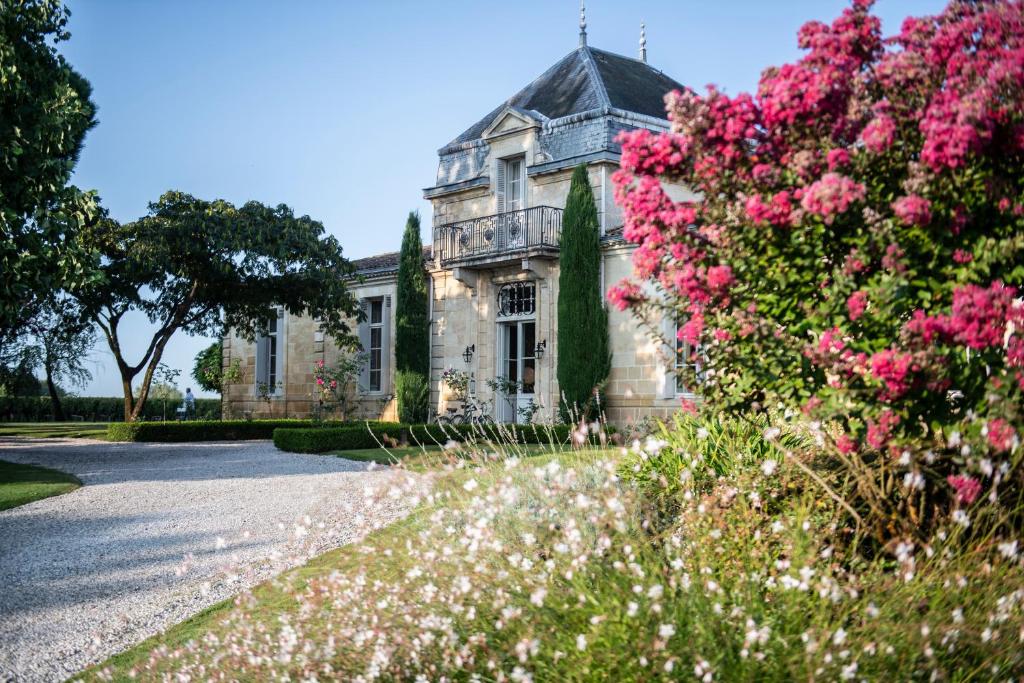 une vieille maison avec des fleurs roses devant elle dans l'établissement Château Cordeillan-Bages, à Pauillac