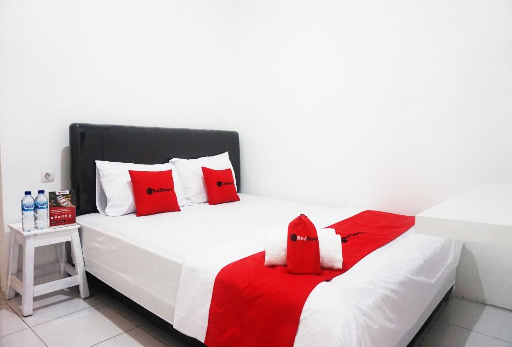 a white bed with red and white pillows on it at RedDoorz @ Jalan Tanjung Blitar in Blitar
