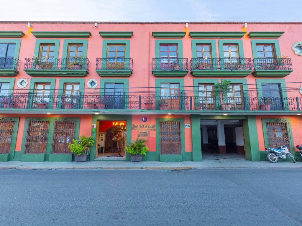 a pink building with windows and balconies on a street at Hotel Valle De Oaxaca in Oaxaca City