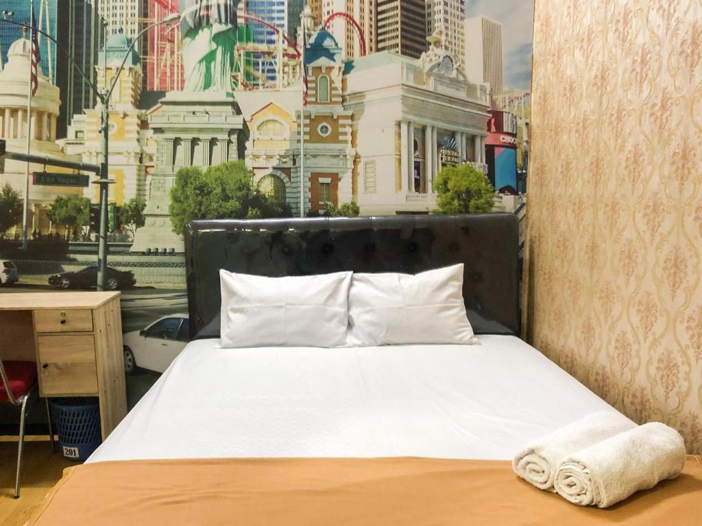 a bed in a room with a view of a city at Gangnam Hotel near Mall Olympic Garden Malang Mitra RedDoorz in Betek