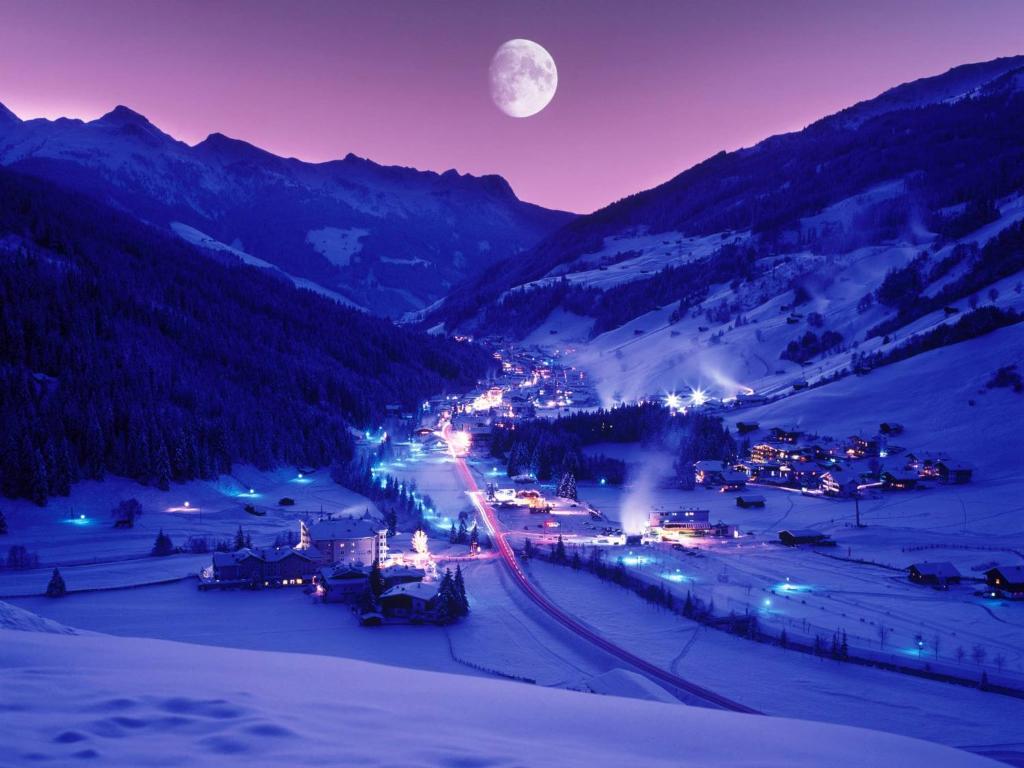 une ville de montagne la nuit sous la pleine lune dans l'établissement Appartements Fürstalm Alpendorf, à Gerlos