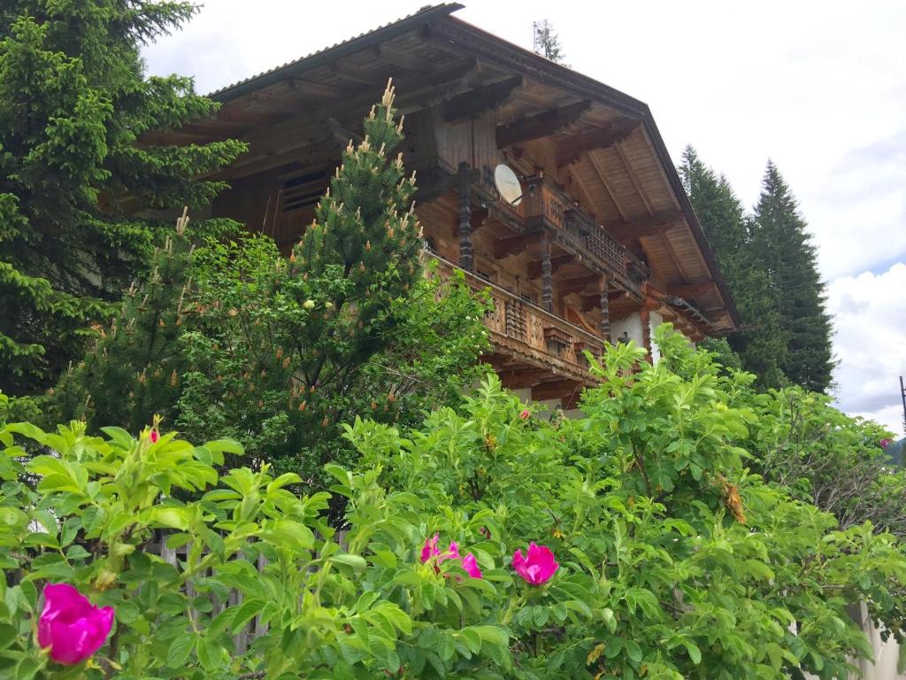a log cabin with pink flowers in front of it at Appartements Fürstalm Alpendorf in Gerlos