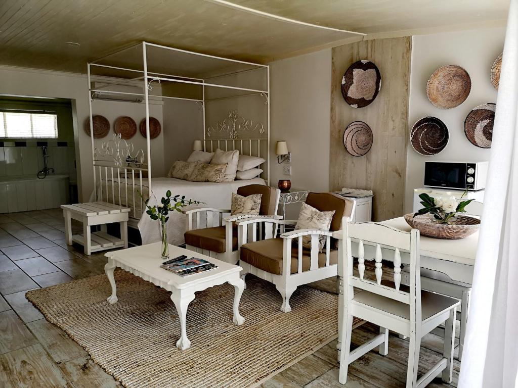 sala de estar con cama, mesa y sillas en Cranberry Cottage, en Ladybrand