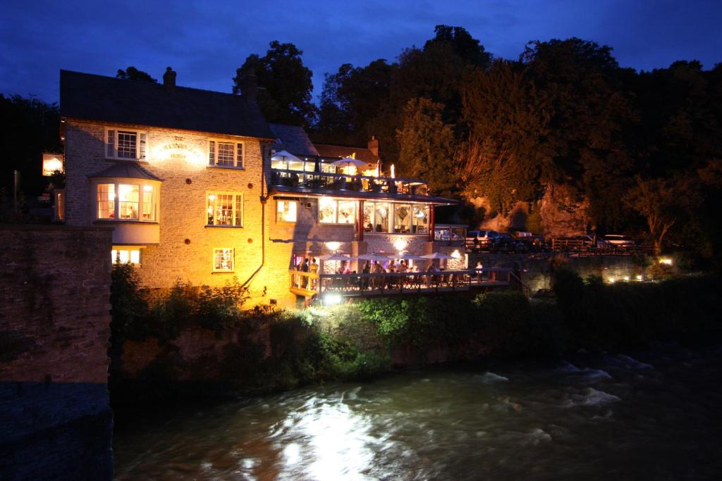 um edifício iluminado ao lado de um rio à noite em The Charlton Arms em Ludlow